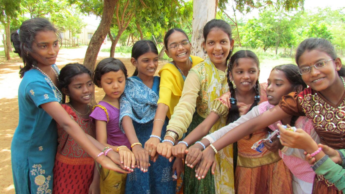 Children put their hands together in a circle