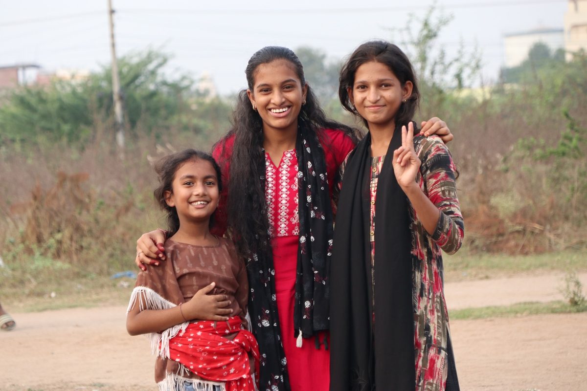 Three girls smile together outdoors